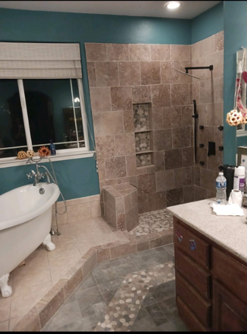 Remodeled bathroom with a tiled curbless walk-in shower, pebble tile floor inlay and clawfoot tub in Fernley, Nevada