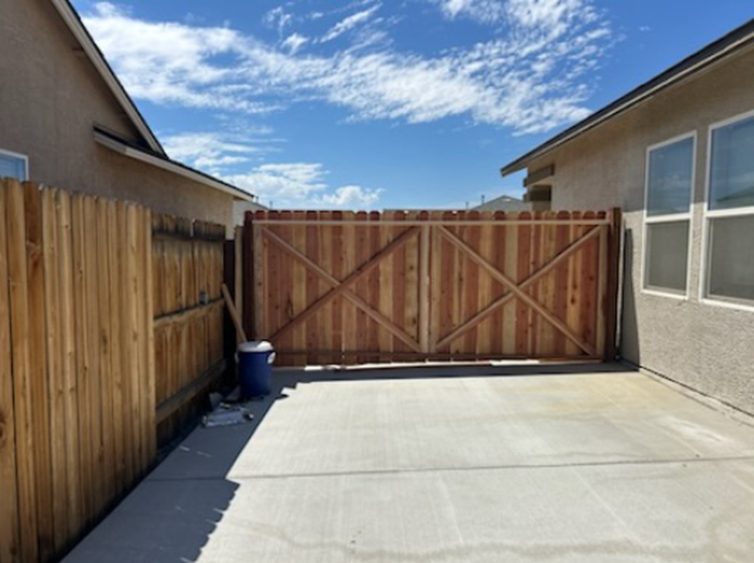 New wood privacy fence with double drive gate beside a finished concrete side yard slab in Fernley NV