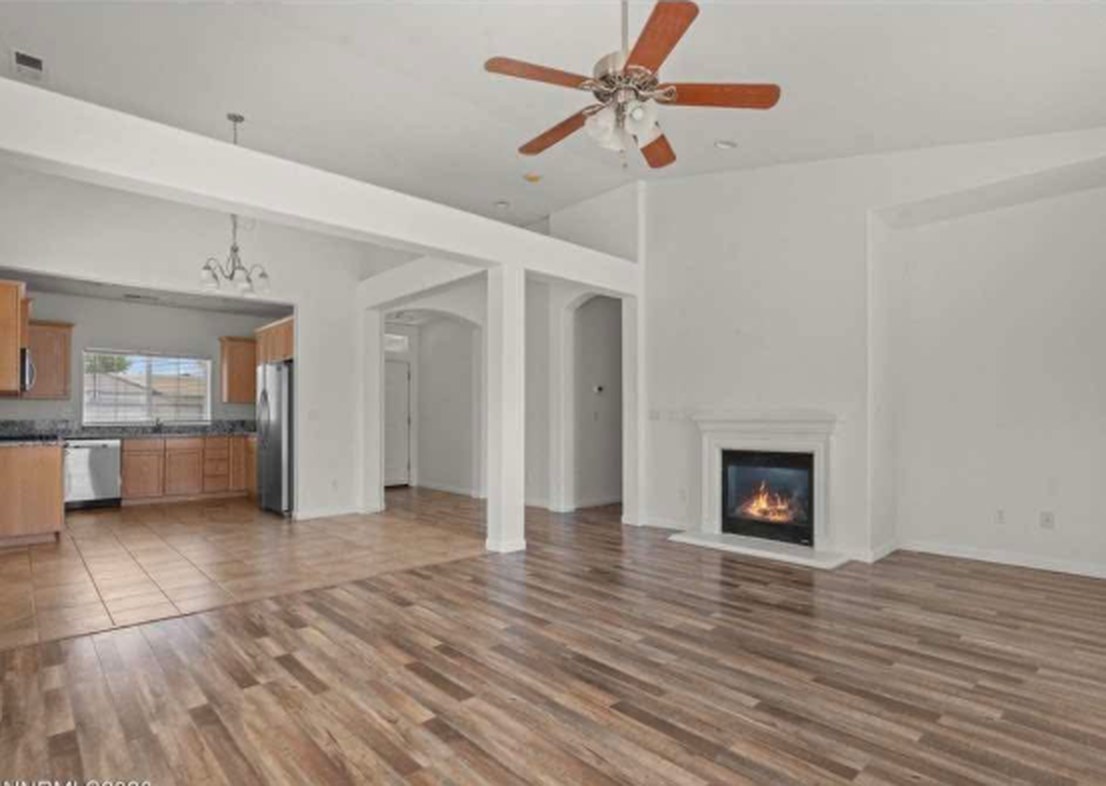 Open living room with new wide-plank wood-look flooring, fireplace and kitchen beyond in a Fernley NV home
