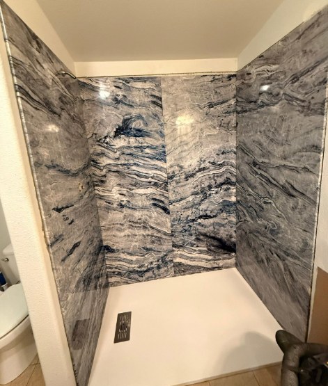 New walk-in shower with large marbled gray and white wall tile from a Fernley NV bathroom remodel